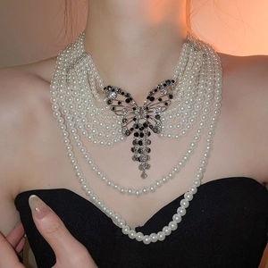 Collier de perles multicouches élégant avec un grand pendentif papillon étincelant.