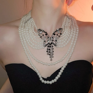 Détail du collier de perles multicouches avec un élégant pendentif papillon en strass