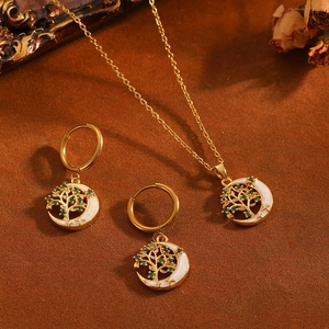 Detalle de collar y pendientes de luna y árbol de la vida dorados con piedras verdes