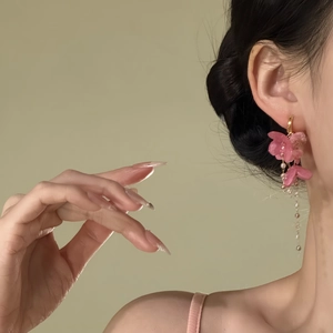 Elegante rosa Blumenohrringe mit Quasten im Detail an einem Model für einen süßen Urlaubslook