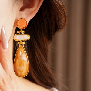 Close-up of vintage resin drop earrings with orange marble effect and gold metal trim