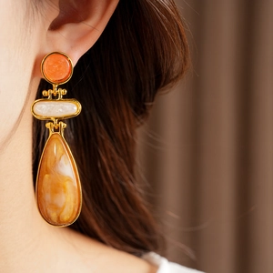Detailed macro view of a vintage-style resin water drop earring worn by a model.