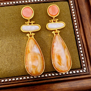 Close-up of vintage resin drop earrings with marble pattern on olive green fabric
