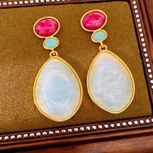 Detailed macro view of vintage resin teardrop earrings with red, blue, and white resin stones