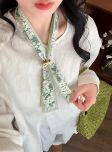 Detailed shot of floral skinny scarf necklace with a cute bow slider on a white shirt