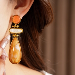 Close-up of vintage gold-tone earrings with resin teardrop and round studs