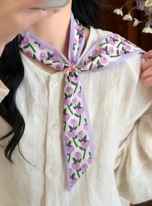 Macro detail showing a purple floral skinny scarf elegantly tied on a white linen shirt