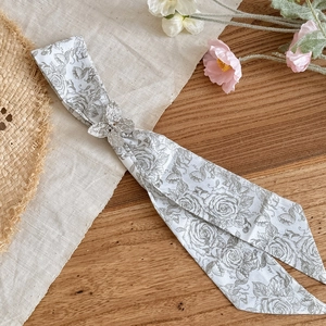 Detailed view of a slim floral print scarf necklace with a delicate butterfly buckle accent.