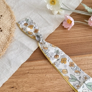 Detailed view of floral print silk scarf with textured silver metal slider clasp