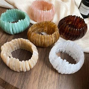 Detail view of vintage acrylic stretch bracelets in multiple marbled colors on dark wood