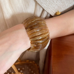 Close-up of a vintage marbled brown acrylic geometric stretch bracelet on a wrist.