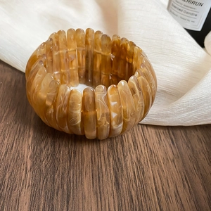 Detailed close-up view of amber acrylic elastic bracelet with a marbled vintage pattern