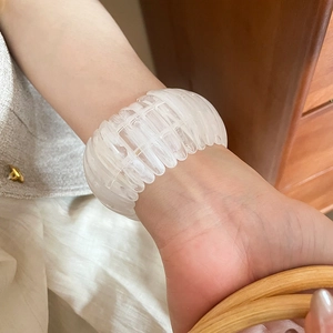 Detailed close-up of a white translucent acrylic elastic bracelet with ribbed texture.