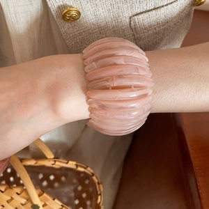 Detail view of pink marbled acrylic elastic ribbed bracelet on wrist with retro style.
