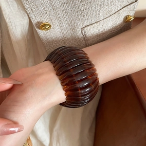 Detail view of a vintage brown acrylic elastic bracelet with geometric segments on wrist