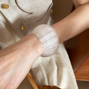 Close-up detail of a white acrylic iridescent geometric elastic bracelet worn on a wrist