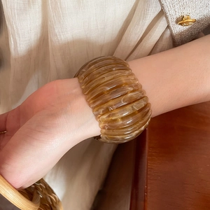 Detailed view of a vintage amber acrylic elastic bracelet with marbling on a wrist.
