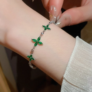 Nahaufnahme eines silberfarbenen Armbands mit grünen Blumen-Zirkoniasteinen an einem Handgelenk