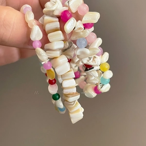 Primer plano detallado de pulsera con conchas irregulares y cuentas de colores estilo dopamina