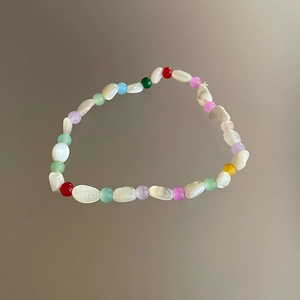 Detalle de una pulsera de cuentas de concha irregulares con vibrantes toques de color