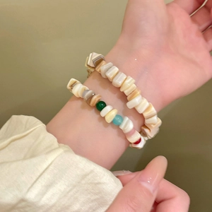 Detalle de cerca de pulseras de cuentas de concha geométricas con acentos de colores vibrantes