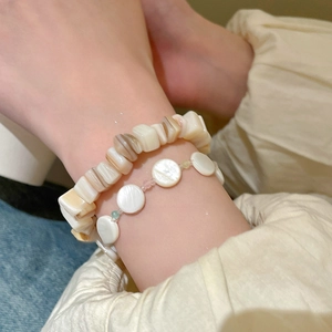 Primer plano de pulseras de cuentas de concha blanca redondas e irregulares en capas