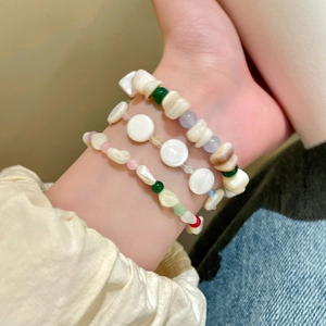 Detalle de pulseras de cuentas de colores y conchas geométricas irregulares en la muñeca