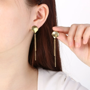 Close-up of gold stainless steel shell tassel earrings worn by a model in detail view