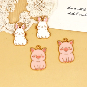Close-up detail of cute enamel rabbit and pig charms for DIY jewelry and bag accessories.