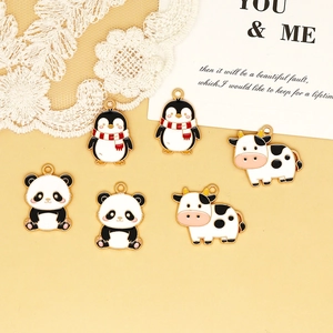 Detailed macro view of cute cartoon panda, penguin, and cow alloy enamel charms for DIY jewelry