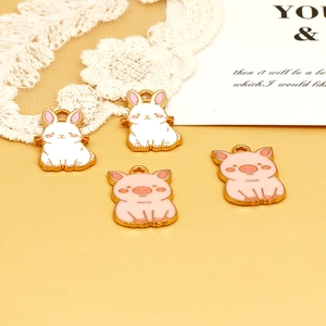 Macro detail of cute cartoon rabbit and pig enamel charms for DIY jewelry making and bag decor