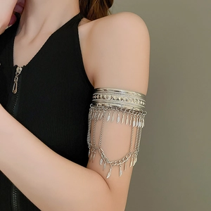 Détail d'un brassard argenté de style punk avec franges de chaîne et breloques plumes sur mannequin