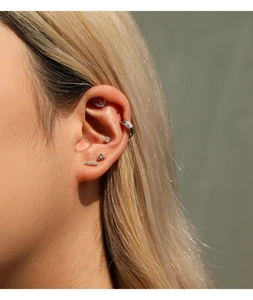 Primer plano detallado de piercings de oreja en plata y moissanita en una modelo rubia