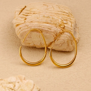 Macro view of minimalist gold-plated stainless steel French hook earrings on natural stone.