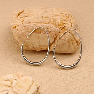 Minimalist stainless steel oval curved ear hooks presented on a natural stone background.