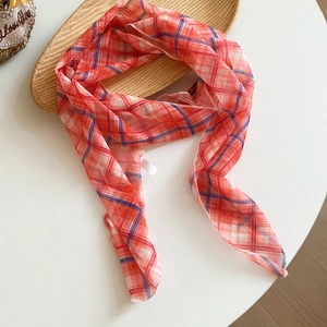 Close-up view of a lightweight retro plaid silk scarf draped on a natural wooden tray.