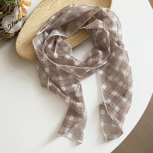 Close-up detail of retro brown plaid lightweight sheer scarf displayed on a white table