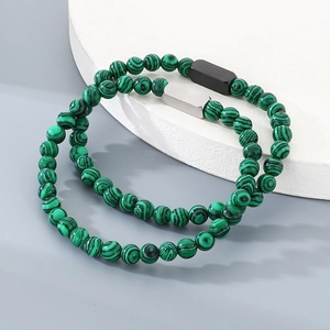 Nahaufnahme von grünen Malachit-Perlenarmbändern mit minimalistischer Metallplakette
