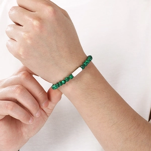 Detailaufnahme eines Malachit-Perlenarmbands für Herren mit silbernem Metallanhänger.
