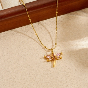 Primo piano di un ciondolo a forma di libellula dorato con eleganti cristalli rosa