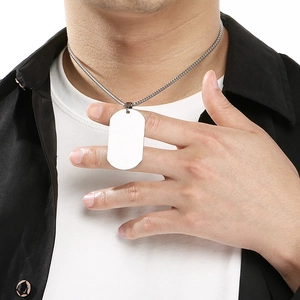 Detailed view of a minimalist silver stainless steel dog tag necklace worn by a male model