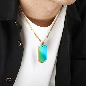 Close-up of rainbow iridescent dog tag pendant on a gold chain necklace.