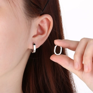 Macro view of minimalist stainless steel U-shaped hoop earrings showing wearing effect