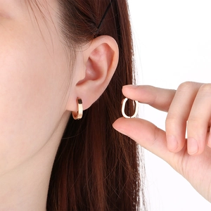 Detailed view of 18k gold plated stainless steel U-shaped hoop earrings on ear.