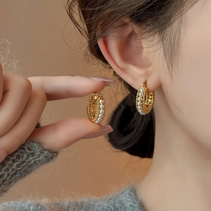 Detailed view of French vintage gold pearl hoop earrings on a model's ear