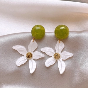 Détail rapproché de boucles d'oreilles fleurs blanches avec perles en résine verte