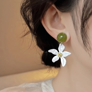 Vue détaillée de la boucle d'oreille étoile de mer blanche avec perle verte sur modèle