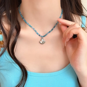 Dettaglio della collana estiva con perle blu e ciondolo a conchiglia sulla modella