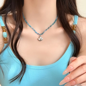 Primo piano di una collana estiva con perline blu e un ciondolo a forma di conchiglia