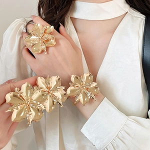 Vista dettagliata di un elegante set anello e bracciale a fiore in metallo dorato su modella